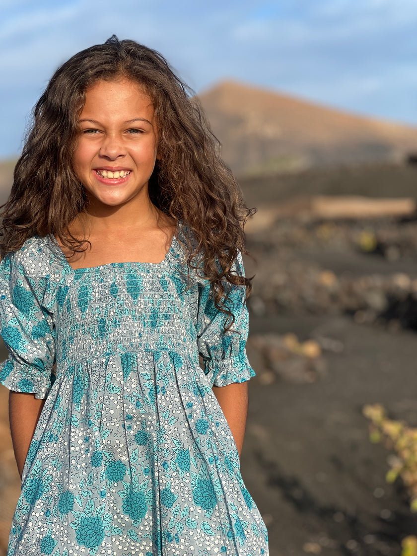 A sweet knee length dress with puff bracelet length sleeves, smocked bodice, square neckline and knee length gathered skirt. In our beautiful green, grey and turquoise chrysanthemum print.